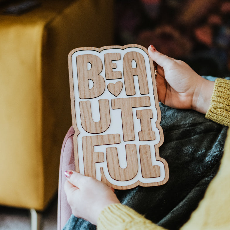 Wooden laser cut wall art featuring a hand drawn font saying 'beautiful'